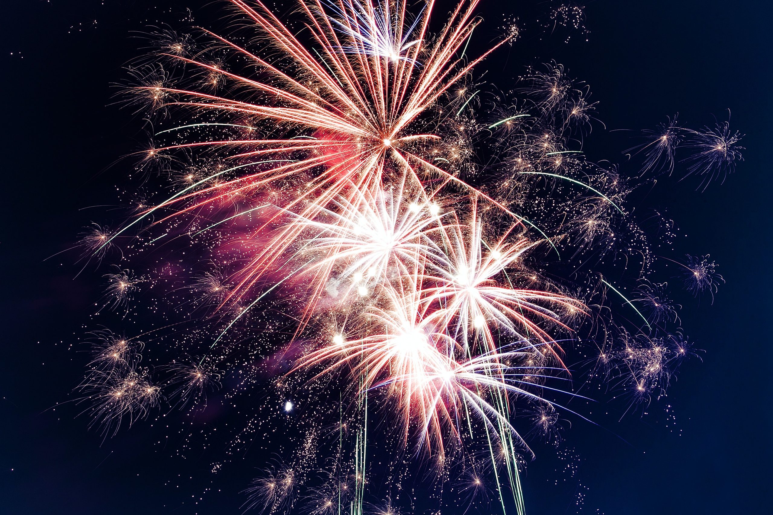 A vibrant display of fireworks in a New Jersey night sky, featuring bursts of white, red, and blue sparks with trails of light.