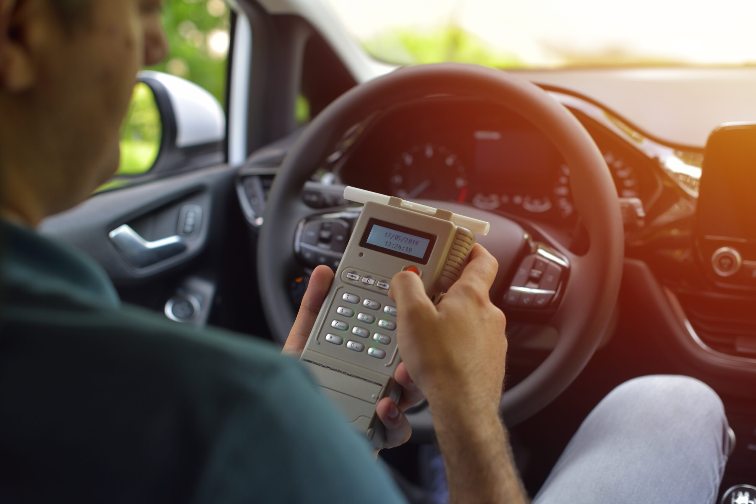 A man in a car holds a calculator displaying 