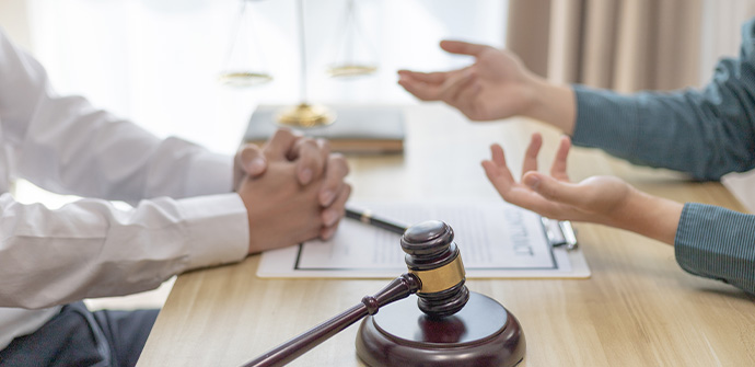 Two people discussing across a table with a wooden gavel and legal documents in the foreground, symbolizing a legal consultation or negotiation with a Bergen County Criminal Defense Attorney.