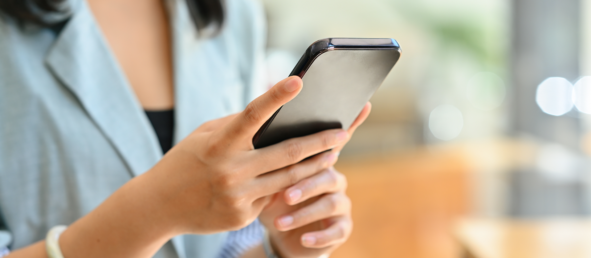 A close-up of a woman's hands holding a smartphone, focusing on the screen with a blurred background.