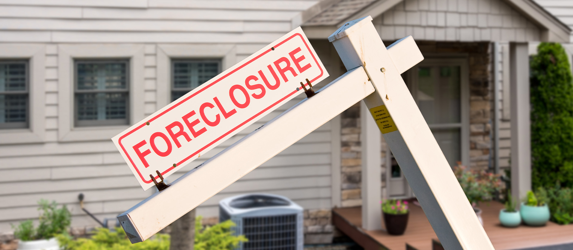 Mockup of a foreclosure sign in front of a modern townhome