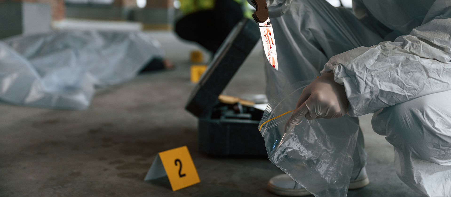 Forensic investigator in a white suit collects evidence at a crime scene, marked by numbered labels, inside an unfinished building.