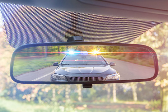 car getting pulled over by police car in rearview mirror