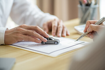 person with mini car and insurance papers and pen