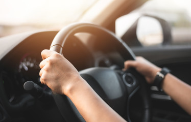 person's hands on wheel of car