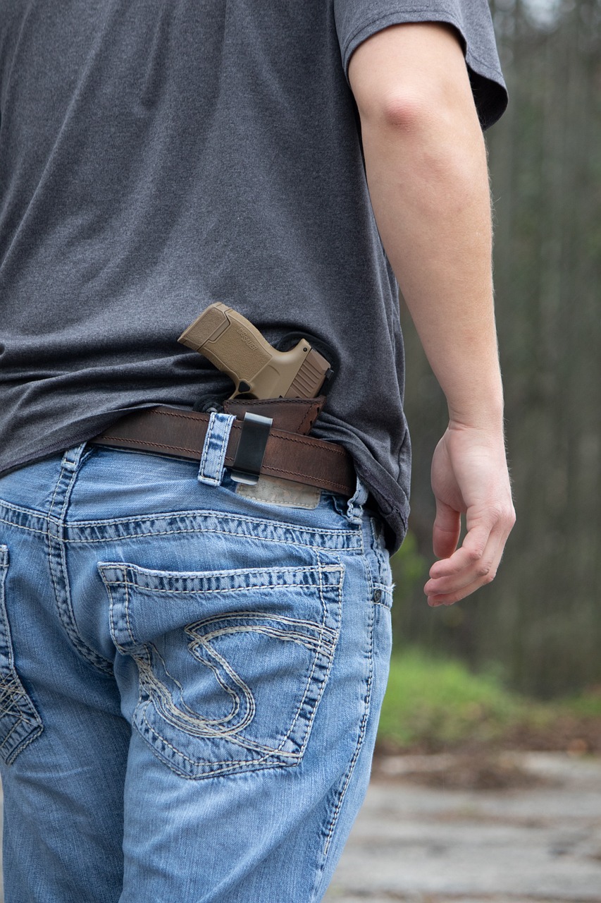 Man seen from behind at waistline with a gun in his concealed belt holster